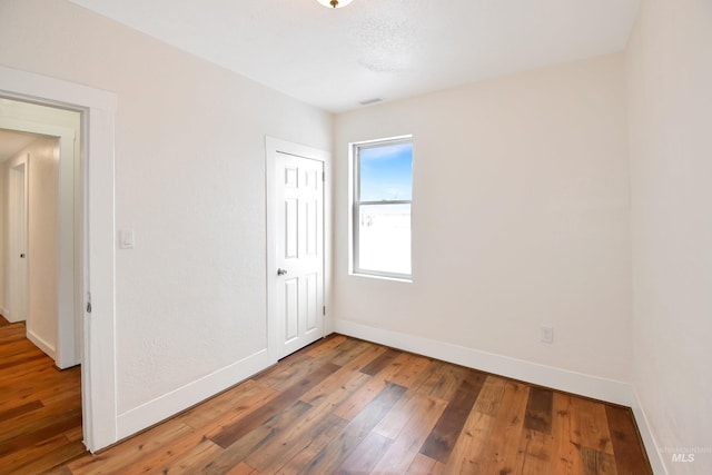 unfurnished room with hardwood / wood-style floors and baseboards