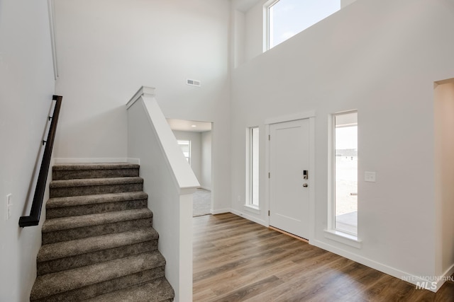 foyer featuring stairway, light wood-type flooring, a healthy amount of sunlight, and visible vents