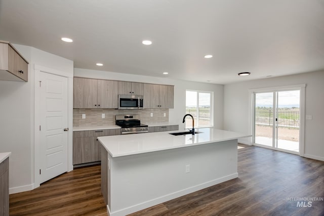 kitchen featuring a sink, a center island with sink, stainless steel appliances, and light countertops