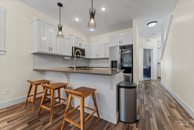 918 N 31st St, Boise, ID 83702 - kitchen with appliances with stainless steel finishes, a peninsula, a kitchen breakfast bar, dark wood-style floors, and recessed lighting