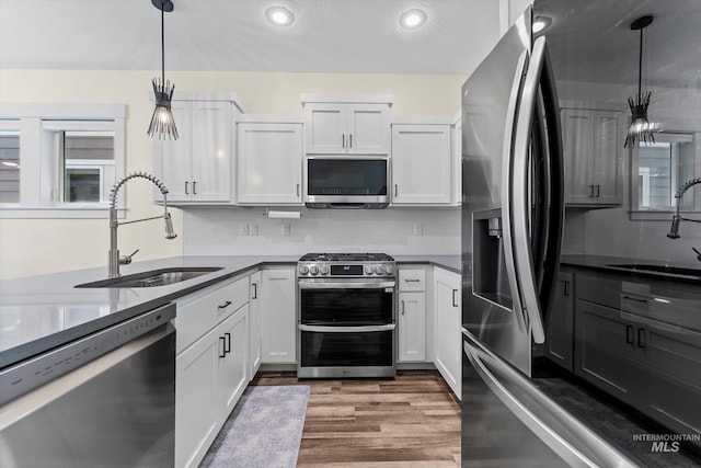 918 N 31st St, Boise, ID 83702 - kitchen featuring appliances with stainless steel finishes, wood finished floors, decorative backsplash, white cabinetry, and decorative light fixtures