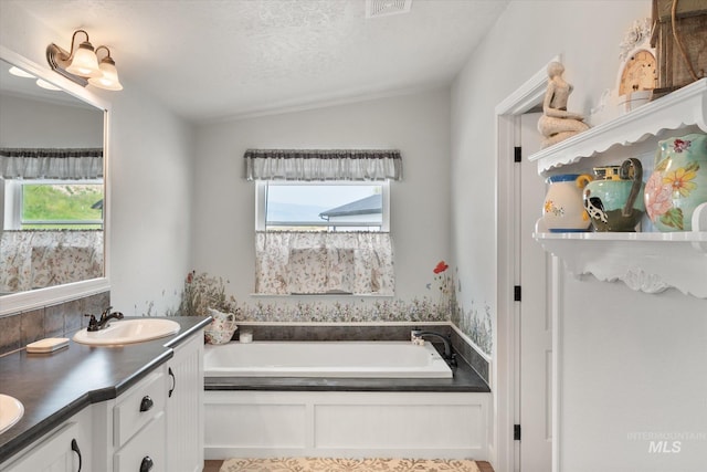 bathroom featuring a tub, vanity, a textured ceiling, and vaulted ceiling