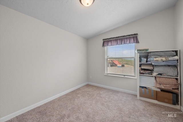 spare room featuring carpet flooring and lofted ceiling