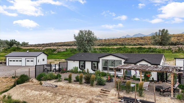 view of front of property featuring a garage, a pergola, and an outbuilding