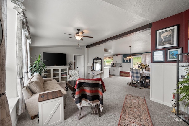 living room featuring a textured ceiling, light carpet, and ceiling fan with notable chandelier