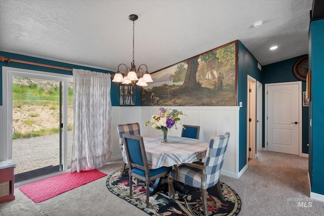 carpeted dining area featuring an inviting chandelier and a textured ceiling