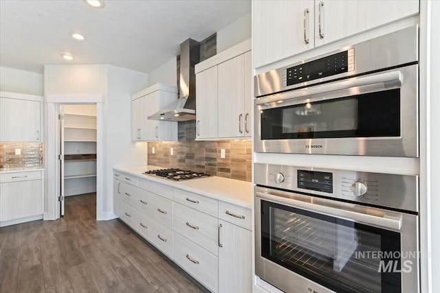 13958 Levendi Ct, Caldwell, ID 83607 - kitchen with wall chimney exhaust hood, stainless steel gas cooktop, tasteful backsplash, light countertops, and dark wood-style floors