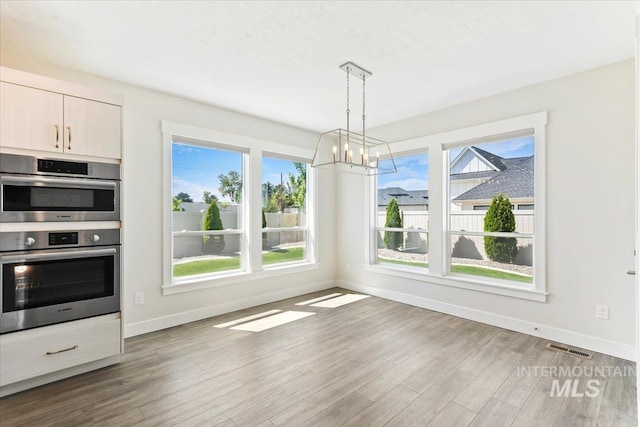 13958 Levendi Ct, Caldwell, ID 83607 - unfurnished dining area featuring baseboards, wood finished floors, and plenty of natural light
