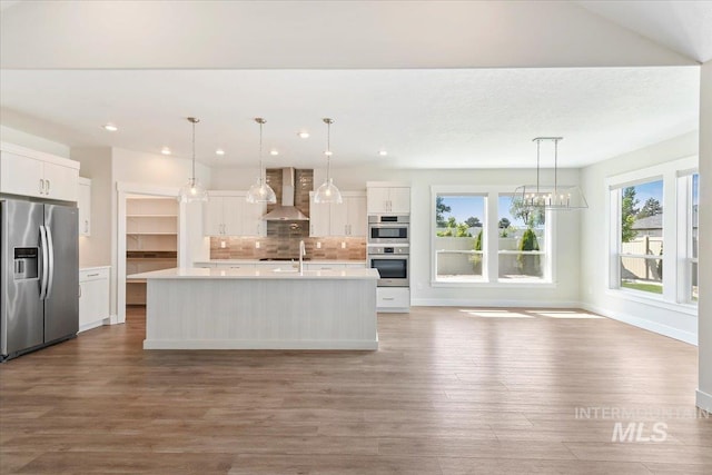 13958 Levendi Ct, Caldwell, ID 83607 - kitchen featuring appliances with stainless steel finishes, wall chimney exhaust hood, light countertops, wood finished floors, and white cabinets