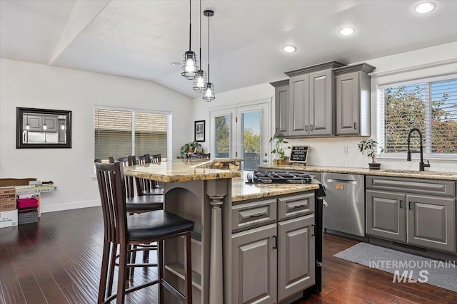 kitchen featuring a kitchen island, a breakfast bar, a sink, gray cabinetry, and stainless steel dishwasher