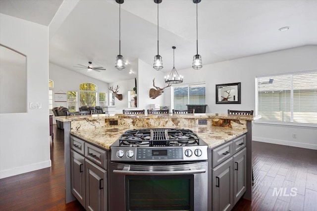 kitchen featuring stainless steel gas stove, light stone countertops, vaulted ceiling, and open floor plan