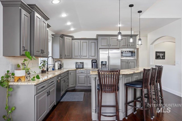 kitchen with a sink, a kitchen island, vaulted ceiling, appliances with stainless steel finishes, and gray cabinets