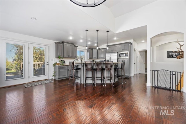 kitchen featuring dark wood-style floors, a kitchen island, decorative light fixtures, stainless steel appliances, and gray cabinets