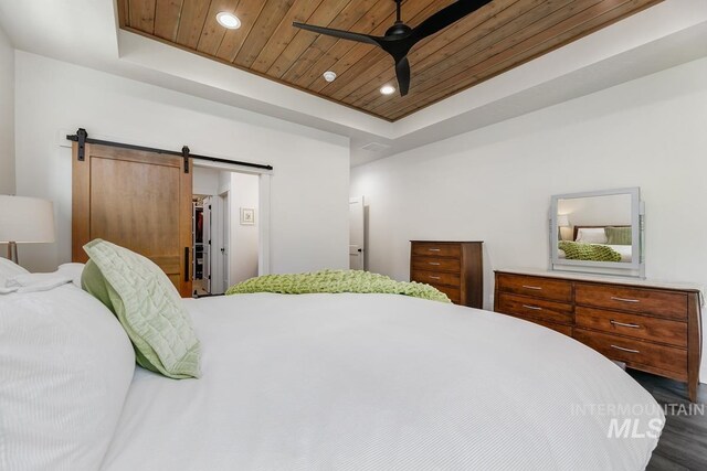 bedroom with a barn door, a tray ceiling, ceiling fan, and wooden ceiling