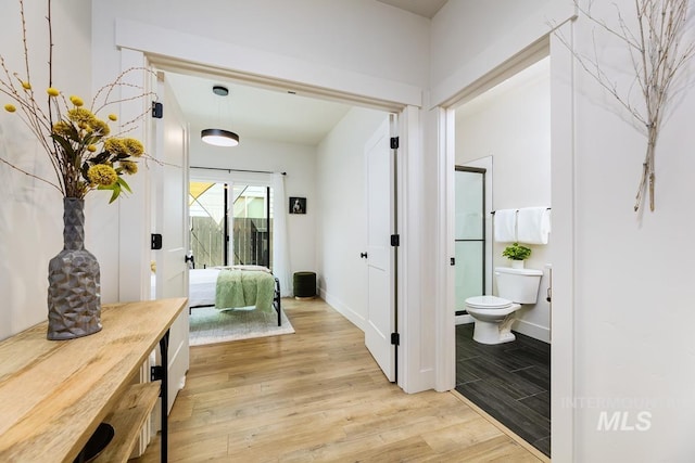 bedroom with light wood-type flooring and connected bathroom