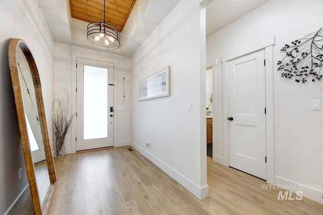 foyer featuring a chandelier, light hardwood / wood-style floors, and wooden ceiling