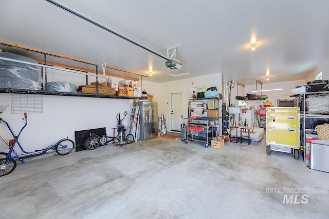 garage featuring stainless steel fridge and a garage door opener