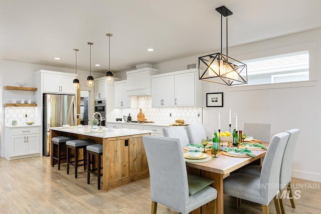 kitchen featuring white cabinets, a kitchen island with sink, and hanging light fixtures