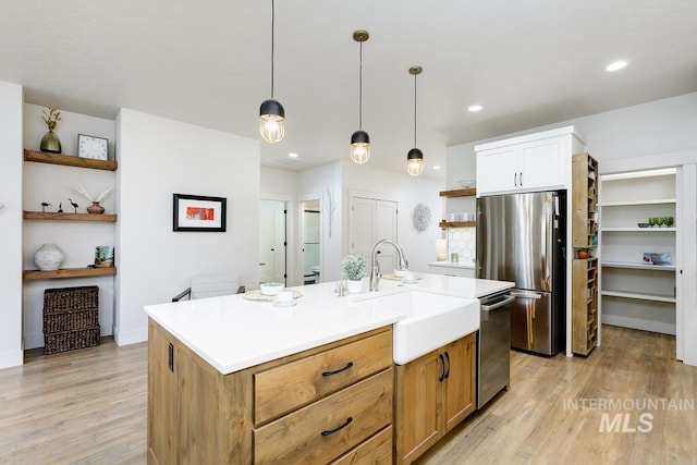 kitchen featuring white cabinetry, sink, hanging light fixtures, a center island with sink, and appliances with stainless steel finishes