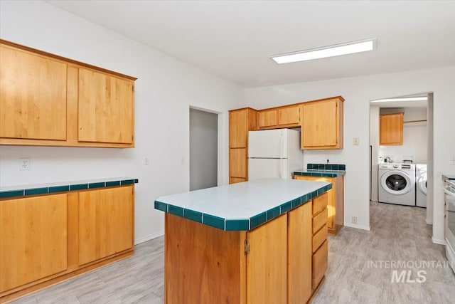1404 River Run Ln, Caldwell, ID 83605 - kitchen featuring freestanding refrigerator, separate washer and dryer, tile countertops, and a kitchen island