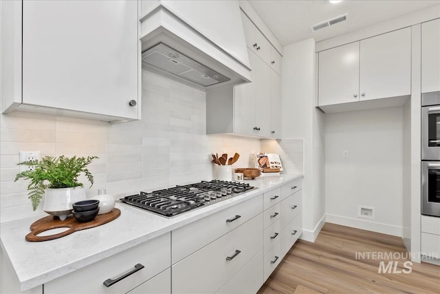 kitchen featuring decorative backsplash, light wood-type flooring, white cabinetry, and stainless steel gas stovetop