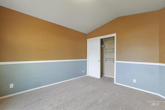 unfurnished bedroom featuring vaulted ceiling, baseboards, carpet, and a closet