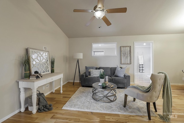 living area featuring ceiling fan, light wood-style floors, baseboards, high vaulted ceiling, and plenty of natural light