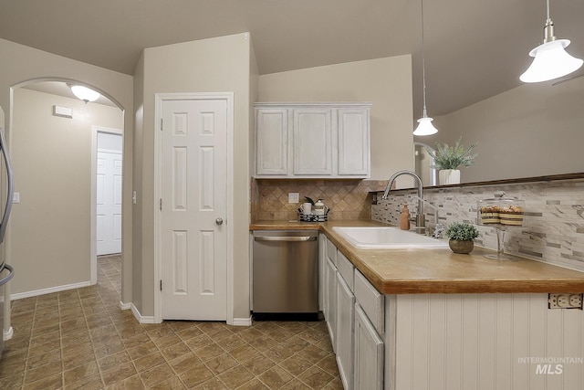 kitchen featuring dishwasher, a sink, arched walkways, decorative backsplash, and vaulted ceiling