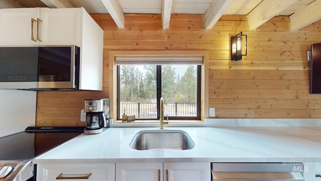 85 Cottage Rd, Anatone, WA 99401 - kitchen with a sink, beam ceiling, dishwashing machine, wooden walls, and white cabinetry