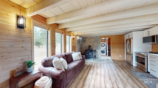 85 Cottage Rd, Anatone, WA 99401 - living room featuring stacked washing machine and dryer, a wood stove, wood walls, light wood-type flooring, and wooden ceiling with exposed beams