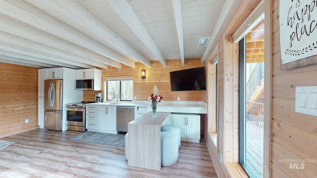 85 Cottage Rd, Anatone, WA 99401 - kitchen with appliances with stainless steel finishes, wood walls, white cabinets, light wood-style floors, and light countertops