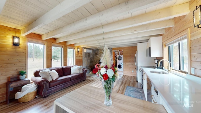 85 Cottage Rd, Anatone, WA 99401 - living room featuring wood walls, stacked washer / drying machine, light wood-style floors, a wall unit AC, and wooden ceiling with exposed beams