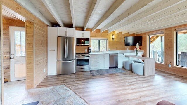 85 Cottage Rd, Anatone, WA 99401 - kitchen featuring appliances with stainless steel finishes, wooden walls, beam ceiling, white cabinets, and light wood finished floors