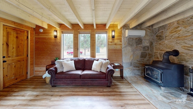 85 Cottage Rd, Anatone, WA 99401 - living area with a wall unit AC, a wood stove, light wood-style floors, wooden walls, and wooden ceiling with exposed beams