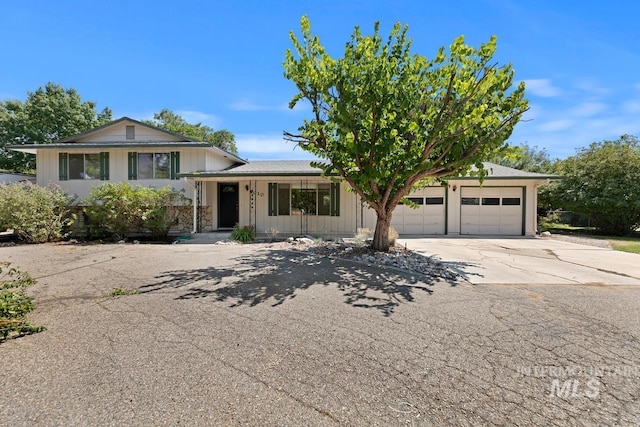tri-level home featuring driveway, an attached garage, and covered porch