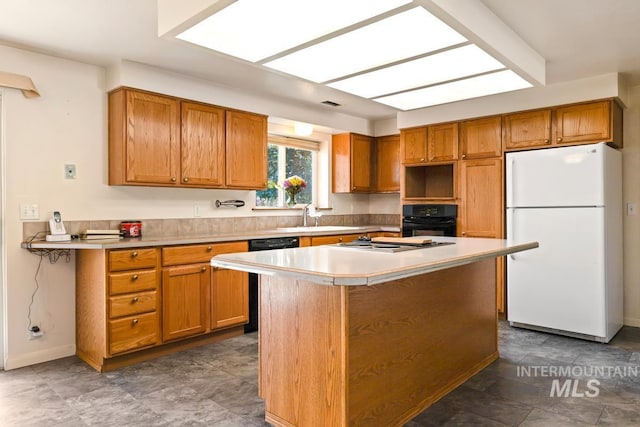 kitchen with freestanding refrigerator, black oven, a sink, stainless steel stovetop, and light countertops