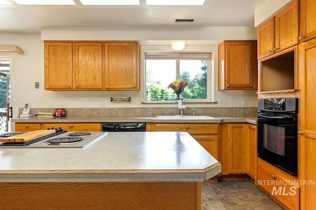 kitchen featuring black appliances, a sink, plenty of natural light, and light countertops