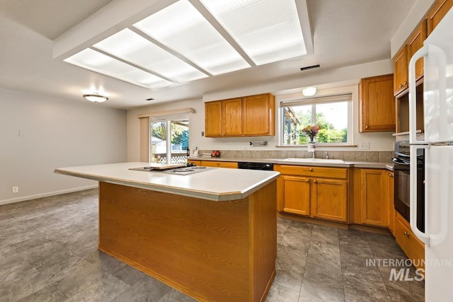 kitchen featuring a sink, black appliances, light countertops, and brown cabinets