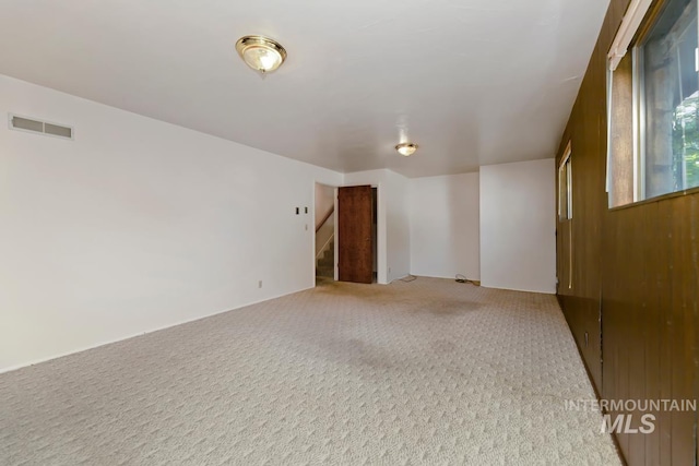 empty room featuring stairway and light carpet