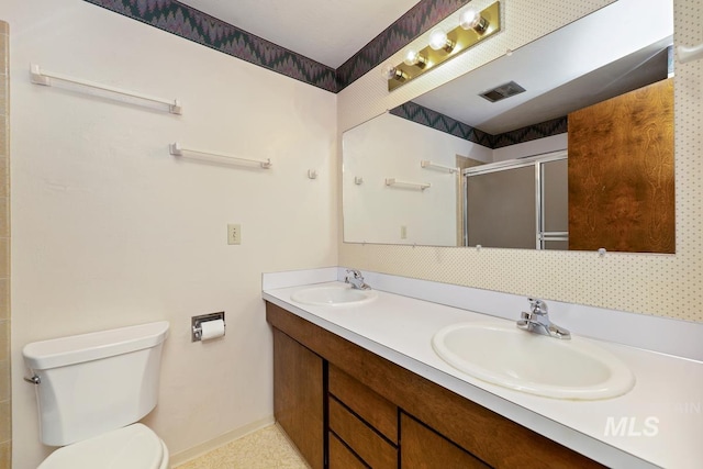 full bath featuring a stall shower, toilet, double vanity, and baseboards
