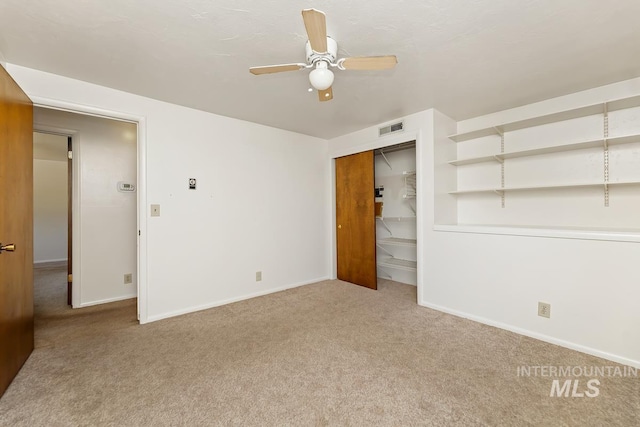 carpeted spare room featuring a ceiling fan and baseboards