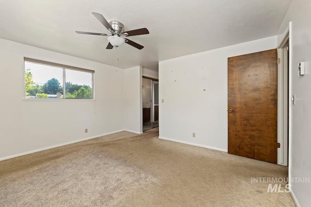 unfurnished bedroom with carpet flooring, baseboards, ensuite bathroom, and a ceiling fan