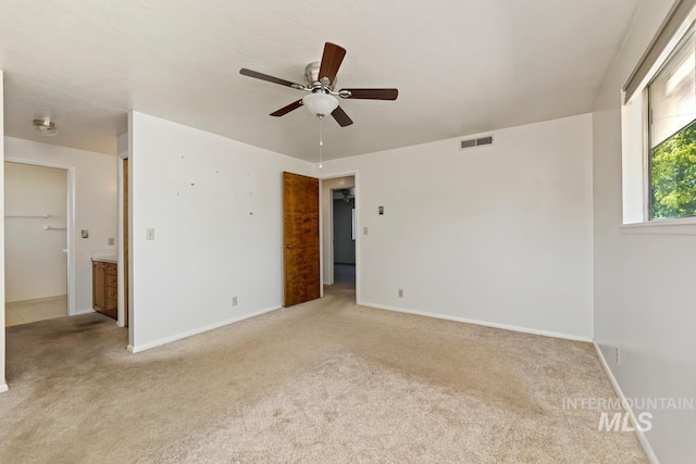 unfurnished bedroom featuring light carpet, baseboards, and a spacious closet