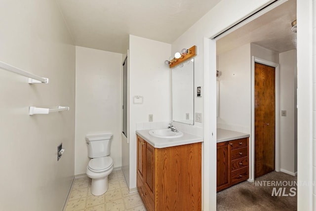 bathroom featuring vanity, toilet, baseboards, and tile patterned floors