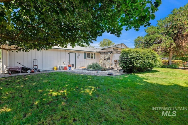 back of house with board and batten siding and a lawn