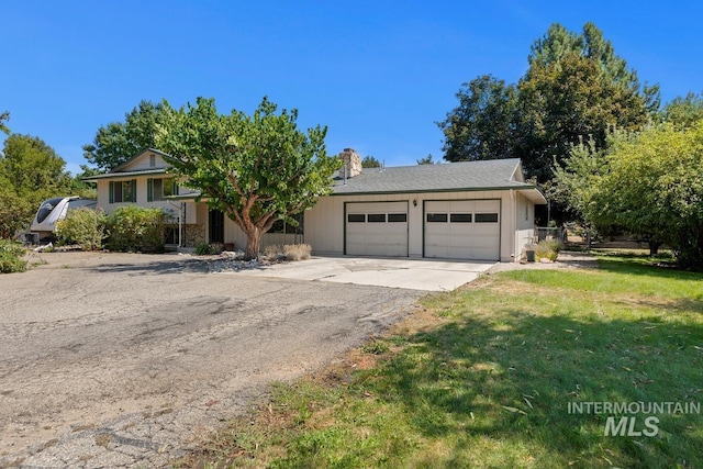 view of front of property with an attached garage, concrete driveway, a front lawn, and a chimney