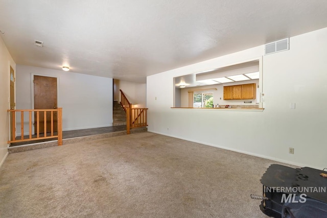 unfurnished living room with stairway, carpet, and baseboards
