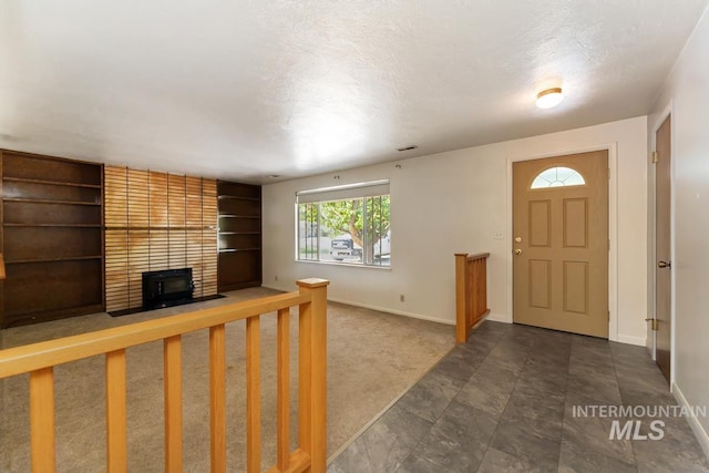 entrance foyer featuring baseboards, a textured ceiling, and a brick fireplace