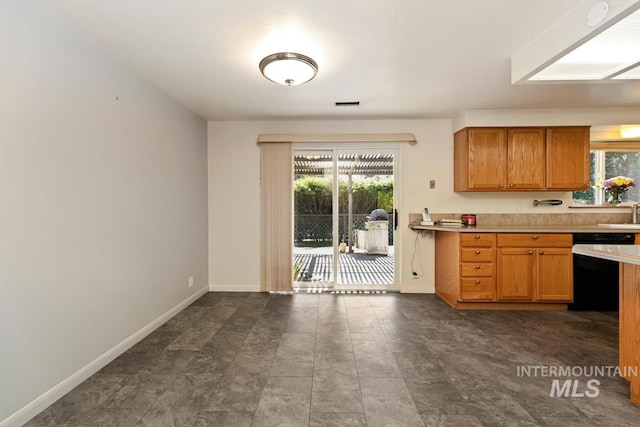 kitchen with dishwashing machine, light countertops, baseboards, and brown cabinetry