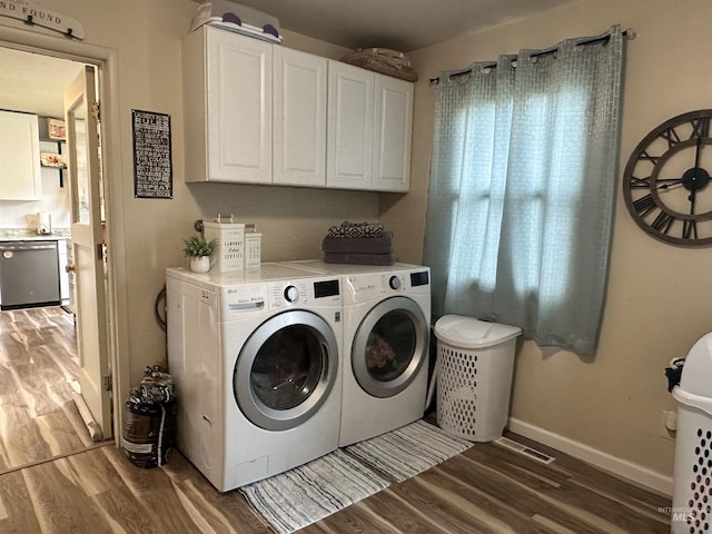 clothes washing area featuring light wood-style floors, separate washer and dryer, baseboards, and cabinet space